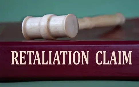 RETALIATION CLAIM- words on a burgundy folder on the background of a judge's gavel