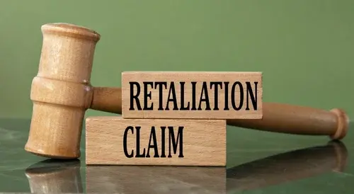 RETALIATION CLAIM - words on wooden blocks with a judge's gavel in the background