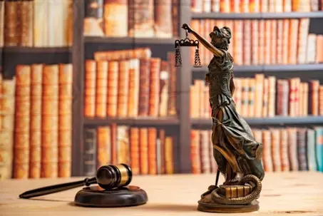 Lawyer office. Statue of Justice, scales and Judge's gavel against the backdrop of a wall of books or a library . Legal law, advice and justice concept