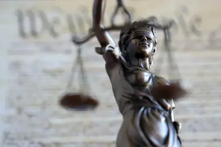 Lady Justice old statue and US Constitution blurred page close up. Lawsuit and justice in United States of America