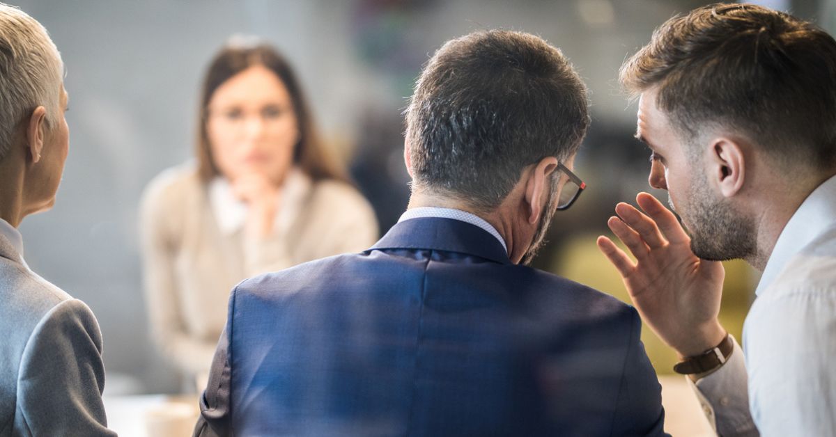 Two men making crude jokes during a work meeting.